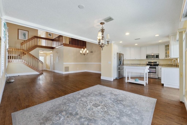 kitchen featuring hanging light fixtures, appliances with stainless steel finishes, a kitchen island, a notable chandelier, and white cabinets