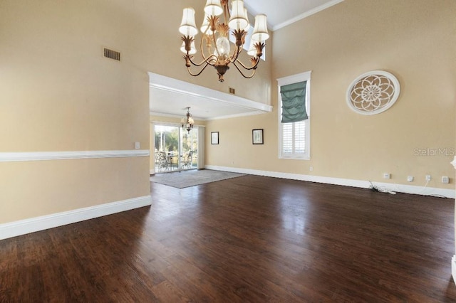 interior space with dark wood-type flooring, crown molding, a chandelier, and a high ceiling