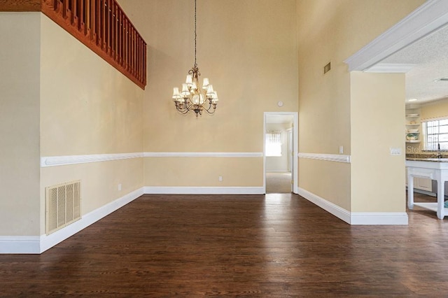 spare room with a notable chandelier, dark hardwood / wood-style floors, and a high ceiling