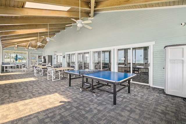 game room featuring wood ceiling, beamed ceiling, ceiling fan, and dark colored carpet