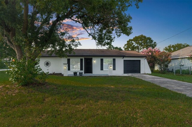 ranch-style home featuring a garage and a yard