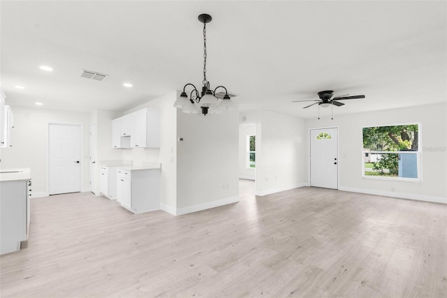 unfurnished living room featuring ceiling fan with notable chandelier and light wood-type flooring