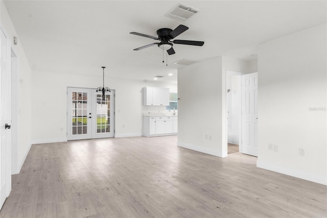 unfurnished living room with ceiling fan with notable chandelier, french doors, and light wood-type flooring