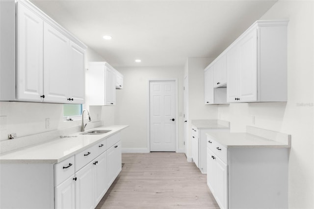 kitchen featuring sink, white cabinetry, and light wood-type flooring