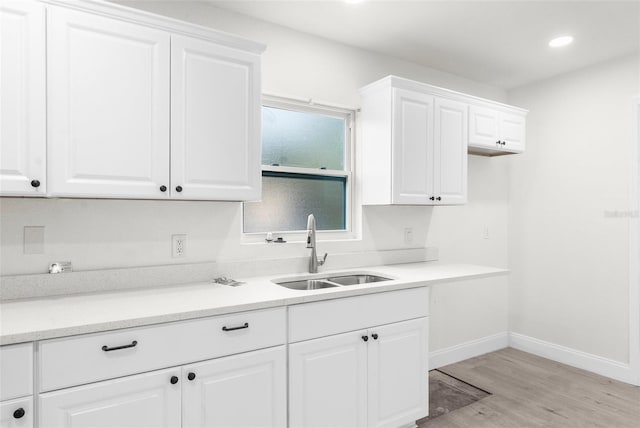 kitchen featuring sink, white cabinetry, and light wood-type flooring