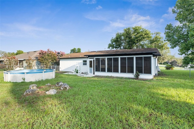 rear view of property featuring a sunroom and a lawn