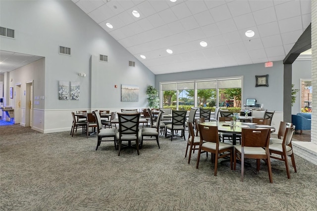 dining room featuring a towering ceiling and carpet floors