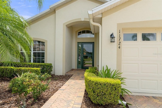 property entrance featuring a garage and stucco siding