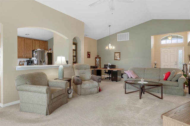 carpeted living room featuring ceiling fan with notable chandelier and vaulted ceiling