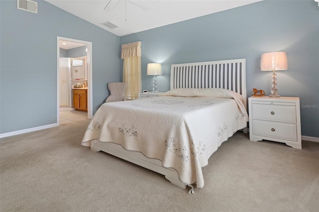 bedroom with lofted ceiling, ensuite bath, and light carpet