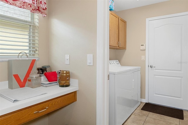 clothes washing area with light tile patterned floors, washer and clothes dryer, and cabinets