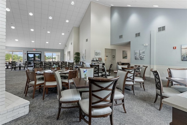 carpeted dining room with a towering ceiling