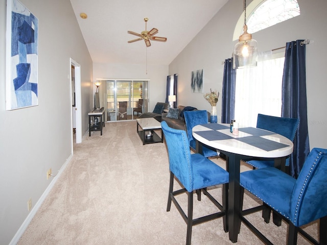 dining area with ceiling fan, plenty of natural light, high vaulted ceiling, and light colored carpet