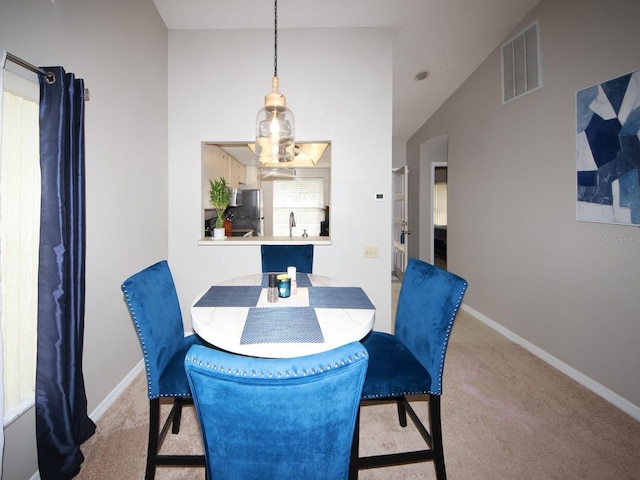 dining space with sink, lofted ceiling, and light carpet