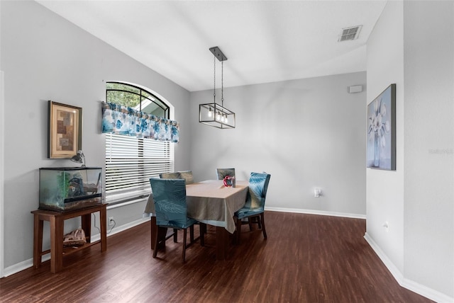 dining area featuring hardwood / wood-style flooring, vaulted ceiling, and an inviting chandelier