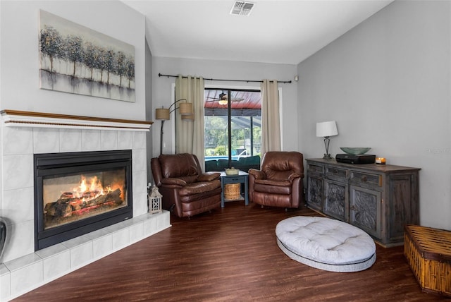 sitting room with dark wood-type flooring and a tiled fireplace