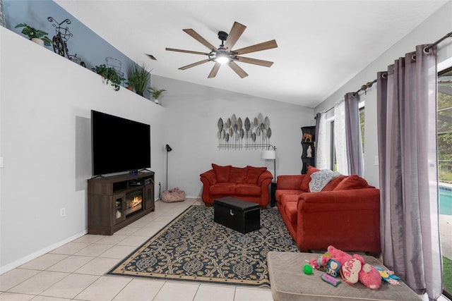 living room featuring ceiling fan, a fireplace, light tile patterned floors, and lofted ceiling