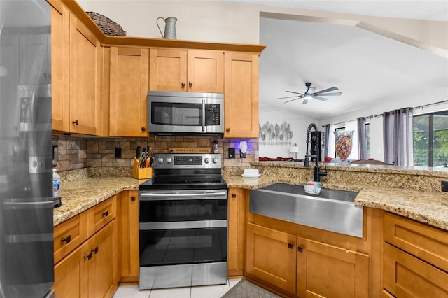 kitchen featuring appliances with stainless steel finishes, light stone countertops, ceiling fan, sink, and backsplash