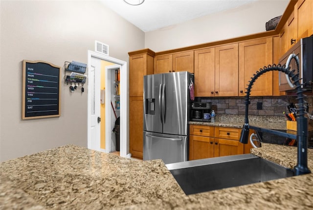 kitchen with appliances with stainless steel finishes, backsplash, and light stone countertops