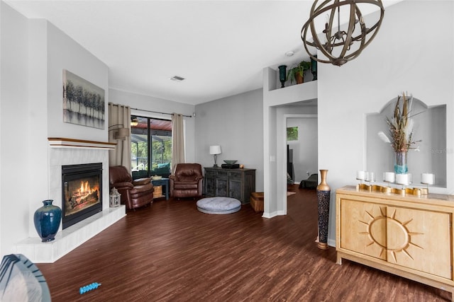 living room with a fireplace, dark wood-type flooring, and a chandelier