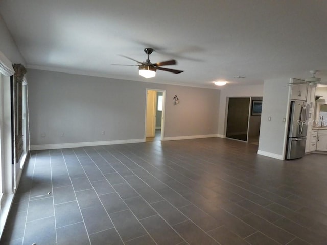 spare room with ceiling fan, ornamental molding, and dark tile patterned floors