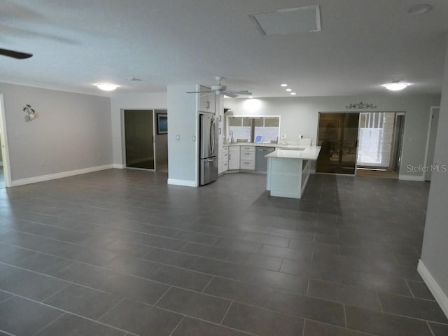 interior space with ceiling fan, a kitchen island, white cabinets, dark tile patterned floors, and stainless steel appliances