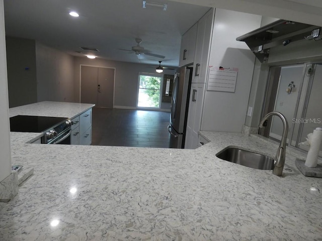 kitchen with ceiling fan, black / electric stove, light stone countertops, sink, and stainless steel fridge