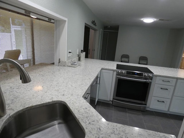 kitchen featuring sink, stainless steel electric range, light stone countertops, and dark tile patterned flooring