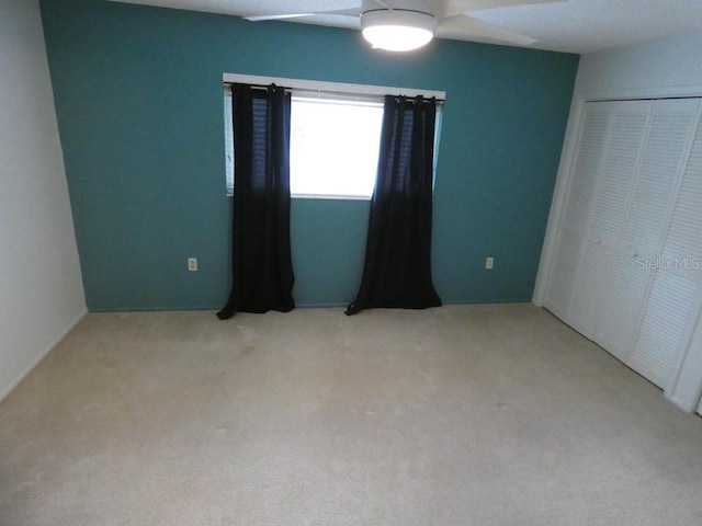 unfurnished bedroom with ceiling fan, carpet, and a closet