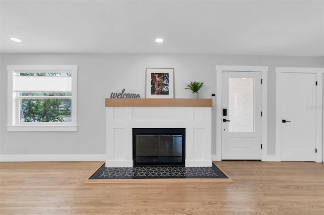 unfurnished living room with a tiled fireplace and light hardwood / wood-style floors