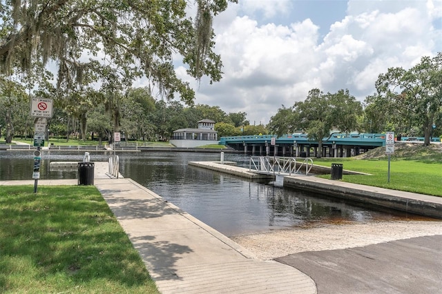 view of dock with a lawn and a water view