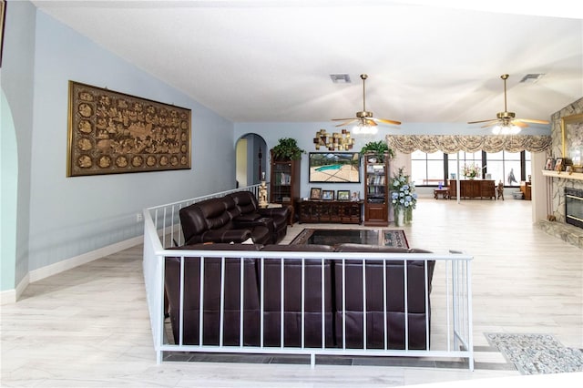 living room with ceiling fan, a fireplace, vaulted ceiling, and light hardwood / wood-style floors