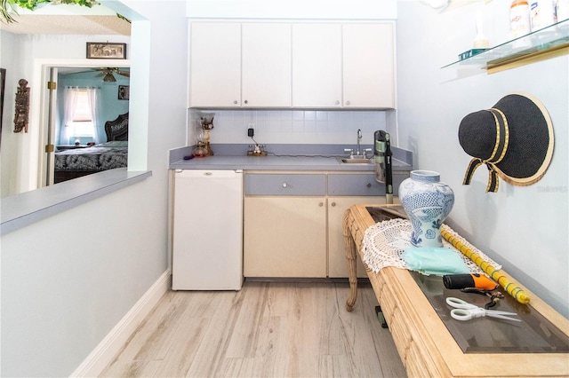 kitchen featuring white cabinetry, white dishwasher, sink, light hardwood / wood-style flooring, and decorative backsplash