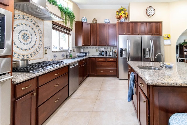 kitchen with decorative backsplash, light stone counters, light tile patterned floors, stainless steel appliances, and sink