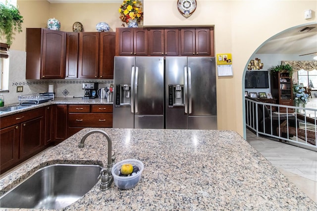 kitchen with decorative backsplash, ceiling fan, light stone countertops, stainless steel fridge, and sink