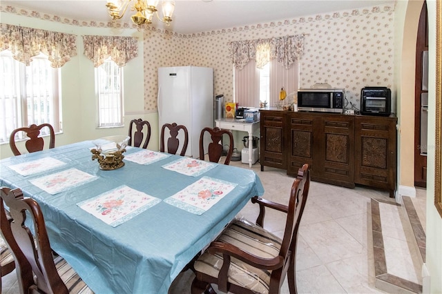 dining space with light tile patterned floors, a healthy amount of sunlight, and an inviting chandelier