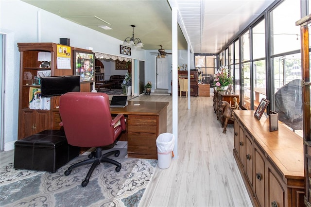 office with ceiling fan with notable chandelier, expansive windows, and light hardwood / wood-style floors