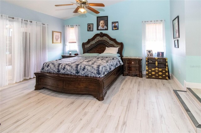 bedroom featuring light hardwood / wood-style flooring, vaulted ceiling, ceiling fan, and multiple windows