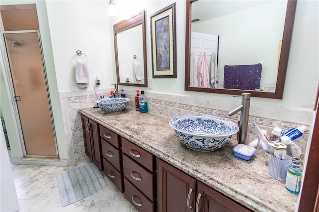 bathroom featuring dual bowl vanity, a shower with shower door, and tile patterned floors