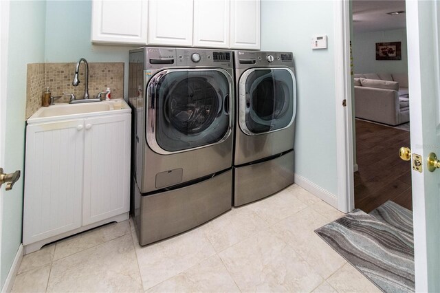 clothes washing area with cabinets, sink, light tile patterned floors, and washer and clothes dryer