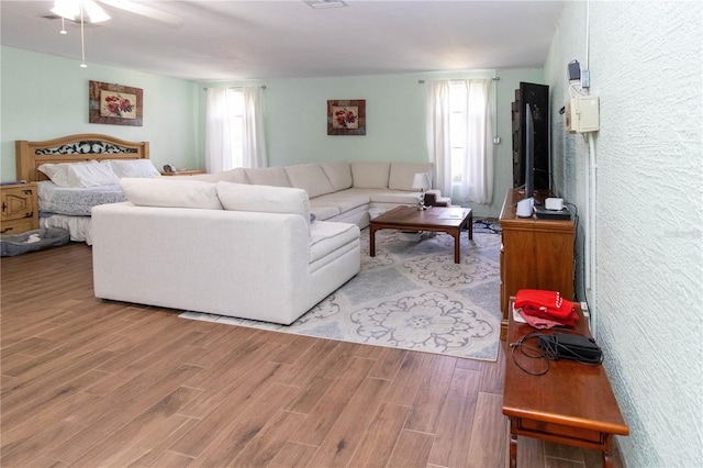 living room featuring ceiling fan, light wood-type flooring, and a healthy amount of sunlight