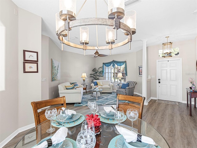 dining room featuring wood-type flooring, a tray ceiling, and decorative columns