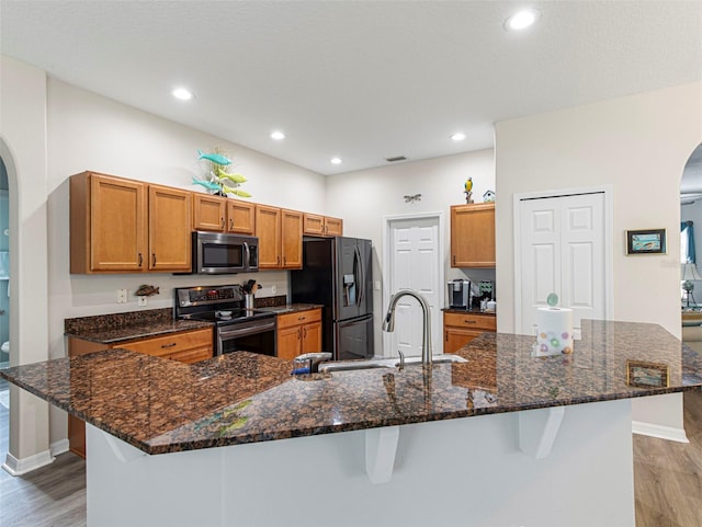 kitchen with a spacious island, appliances with stainless steel finishes, a kitchen breakfast bar, and light hardwood / wood-style flooring