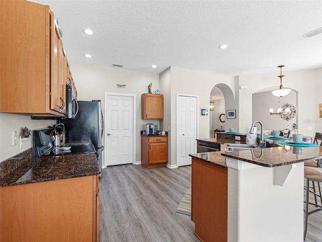 kitchen featuring hanging light fixtures, light wood-type flooring, a textured ceiling, sink, and a notable chandelier