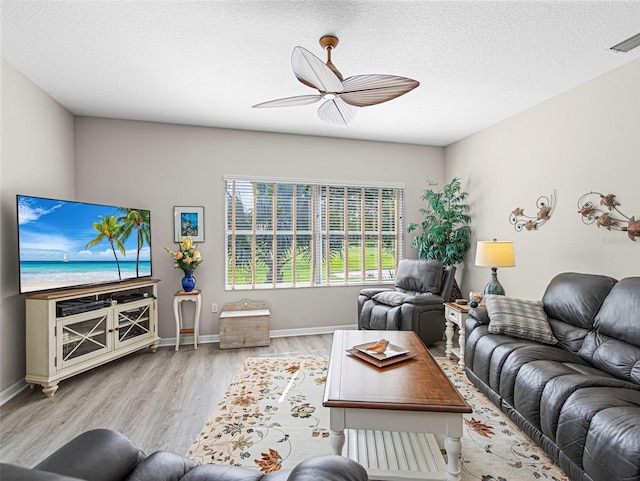 living room with a textured ceiling, light hardwood / wood-style floors, and ceiling fan