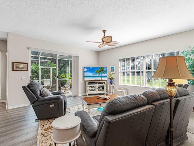 living room featuring light wood-type flooring, a textured ceiling, and ceiling fan