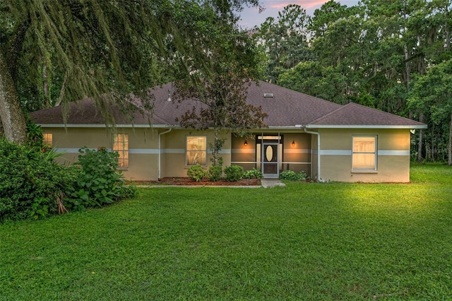 view of front of property featuring a front lawn, a shingled roof, and stucco siding