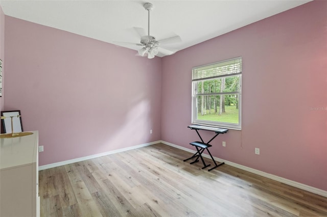 empty room with wood finished floors, a ceiling fan, and baseboards