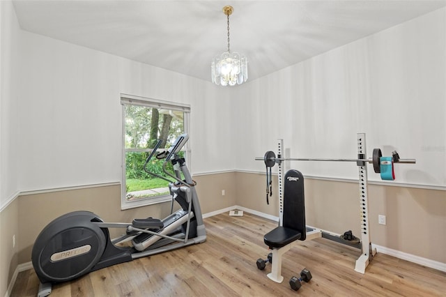 exercise area with an inviting chandelier, baseboards, and wood finished floors