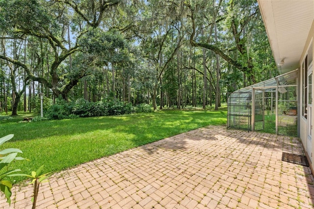 view of patio featuring a greenhouse and an outbuilding